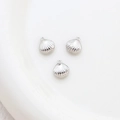 Detailed view of three silver shell-shaped pendants with small loops on white ceramic - 9# Silver Shell