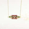Detail of gold evil eye necklace pendant with red green enamel and inscribed WILL text - WILL/Evil Eye/Red Green White