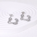 Unregelmäßige Ohrstecker aus silbernem Edelstahl auf einem gewellten Präsentieständer - Stahlfarbe