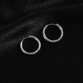 Detailed close-up of twisted silver-colored titanium steel hoop earrings on black velvet - Twisted Hoop / Steel