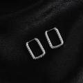 Close-up of silver rectangular hoop earrings with hammered texture on black satin - Rectangle Embossed / Steel