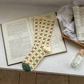 Calze beige con motivi floreali arancioni e punte verdi su un libro d'epoca - Beige Trifoglio Floreale