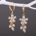 Elegante goldene Blumenohrringe mit klaren Zirkonia-Kristallen an einem weißen Zweig - Weiß