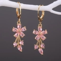 Detail von goldenen Blumenohrringen mit rosa Zirkonia und kristallenen Quasten - Rosa