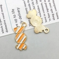Detail of candy-shaped enamel pendants with orange stripes and gold-plated textured backs - Orange Candy (21*10mm)