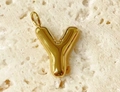 Close-up of a glossy gold bubble letter Y pendant on a textured white stone surface - Letter-Y / Steel