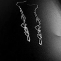 Macro detail of gothic silver earrings featuring human skeleton and bat wing designs - Skeleton