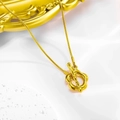 Macro di una collana dorata con chiusura a T a forma di fiore su sfondo materico bianco - Collana / Oro