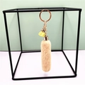 Detail of plush faux fur keychain with yellow tassel and metal ring on minimal background - Beige