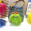 Detailed close-up of a green furry monster keychain with orange ears on a denim bag - Single Piece / Green