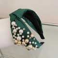 Detailed close-up of dark green fabric headband featuring mixed size pearl embellishments - Green