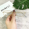 Detail of slim gold geometric metal sunglasses frame with grey ear tips held by hand - Gold Frame Clear Lens