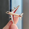 Moderno broche de avión en aleación dorada con detalles de esmalte en la mano - Rojo