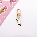 Close-up of cute alloy cat keychain with golden lobster clasp and white spotted cat charm - White Black Spot Cat