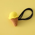 Detalle macro de coletero de ganchillo con forma de helado tejido en amarillo y goma negra - Helado