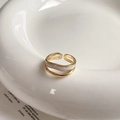 Close-up of double-layered gold ring with zircon squares and wavy band on ceramic plate - Ripple Double Layer