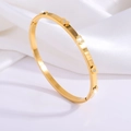 Detalle de brazalete de corazón en acero de titanio dorado con diamantes sobre seda blanca - Corazón Dorado con Diamantes