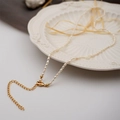 Elegant mini freshwater pearl necklace with gold lobster clasp on white ceramic plate - Seed Beads