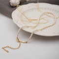 Miniature freshwater pearl necklace with gold-plated lobster clasp on white ceramic - Flat Bead