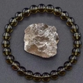 Detail of dark brown crystal beaded bracelet with natural raw gemstone on textured grey surface - Dark Brown Crystal