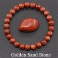 Macro detail of red-brown golden sand stone beads and teardrop pendant on textured surface - Gold Sandstone