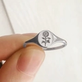 Close-up of a silver signet ring featuring a detailed sunflower engraving on oval face - US 5 / White Gold