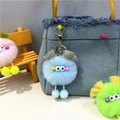 Close-up of blue monster plush keychain with googly eyes hanging on a denim bag strap - Sky Blue