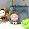 Cute plush monster bag charm with pom-pom legs on blue denim bag and mini wooden stool - Pink