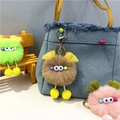 Close-up of cute plush doll keychains in various colors hanging on a blue denim bag - Khaki