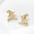 Detalle de pendientes chapados en oro con forma de sombrero de bruja y escoba con piedras - Oro de 18K