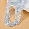 Close-up of 3mm blue and white gradient faceted crystal beads on a white plate - Tiffany Blue
