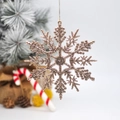 Sparkling gold glitter snowflake ornament hanging on a festive Christmas tree - Rose Gold