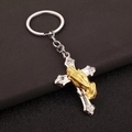 Détail macro du porte-clés croix en argent avec mains en prière dorées sur cuir - Porte-clés / Argenté