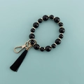 Dettaglio catena per telefono con perline nere, anello dorato e nappa decorativa - Nero