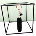 Detail of a black plush faux fur keychain with gold-tone hardware and a metal keyring - Black
