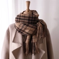 Detail of brown and black plaid scarf with fringe on a beige coat mannequin - Brown & Black Plaid