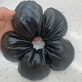 Detail eines großen schwarzen Haargummis aus Kunstleder mit glänzender Blumenstruktur - 3D Blume (Kunstleder) / Schwarz