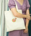 Close-up of a cream canvas tote bag featuring a small embroidered watermelon on a model - Watermelon Red