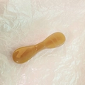 Macro shot of an amber-colored resin facial massage tool on soft pink paper - Caramel color