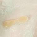 Detail of cream yellow translucent resin cosmetic spatula on white textured paper background - Apricot
