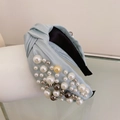 Close-up of light blue fabric knotted headband with elegant pearl and bead details - Blue