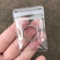 Silver stainless steel band ring inside a clear PVC self-sealing jewelry storage bag - 100 Pieces / 4*6cm (26 Microns)