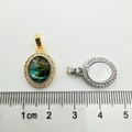 Macro view of shell pendants in gold and silver frames next to a measurement ruler - Oval-shaped White K (white Shell)