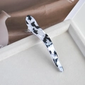 Close-up of a large black and white tortoiseshell acetate shark hair claw on a beige tray - 3# Black & White Pearlescent Curved Horn Clip
