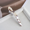 Detailed close-up of large acetate claw clip with tortoise pattern on beige velvet tray - 4# White & Brown Pearlescent Curved Horn Clip