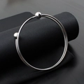 Detail of silver stainless steel open bangle with double ball ends on black fabric - Steel Color