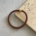 Detail of a brown woven elastic hair tie with a gold metal fastener on a stone base - Light Coffee