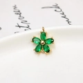 Macro shot of a gold flower pendant with five marquise-cut green zircon petals on ceramic - Green