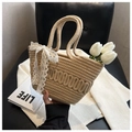 Close-up of khaki straw bucket bag with white lace bow detail held by hand in soft light - Lace Bow Style / Khaki
