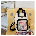 Weiße Ita-Bag mit Sichtfenster und schwarzen Trägern auf einem gelben Stuhl - Weiß und Schwarz